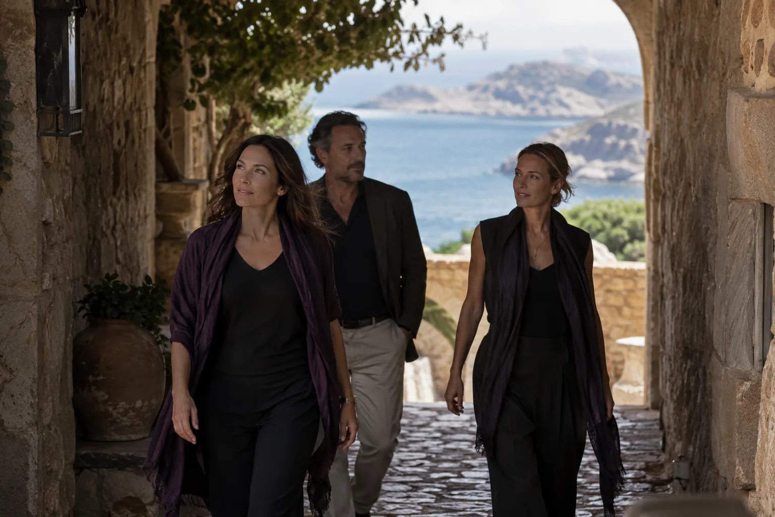 Three members of an eleven-person cohort arriving through a shaded stone passage